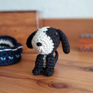 black and white dog ornament, tiny crocheted puppy dog sitting on a bedside table