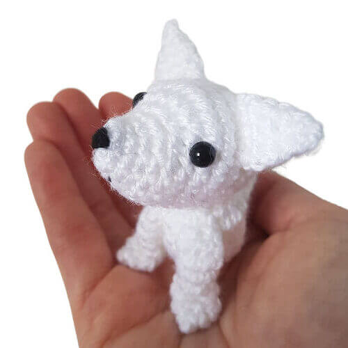 The artic wolf pup crochet art figure in the palm of a hand