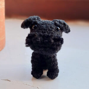 A very sweet black miniature schnauzer gift crochet figure sitting on a window ledge