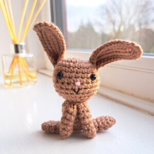 Brown rabbit crochet ornament sitting on a sunny window sill