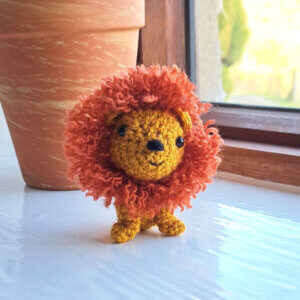 Lion ornament, cute crochet lion figure sitting on a sunny window sill