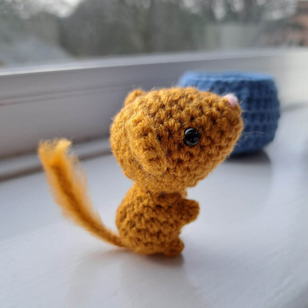 A cute little dormouse ornament crochet art figure sitting on a window sill