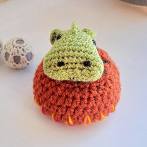 Green dragon ornament hatchling crochet art figure, sitting in cosy embroidered nest