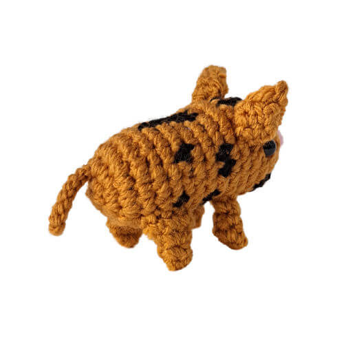 A tiny spotted piglet crochet figure from behind