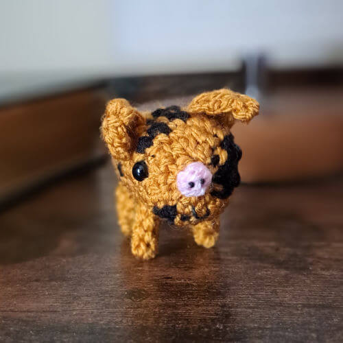 A gold and black spotted piglet on a bedside table