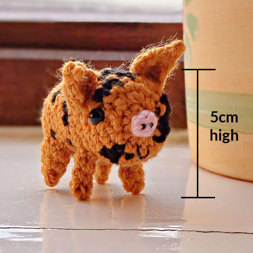 A crocheted piglet ornament with measurement saying 5cm high
