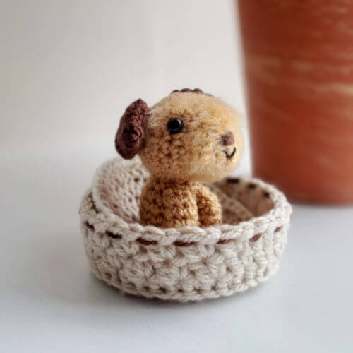 a brown border terrier gift crochet art figure sitting on a window ledge in a cute little crochet bed
