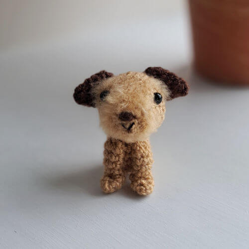 A cute little border terrier gift crocheted in miniature with a tan body and dark brown ears