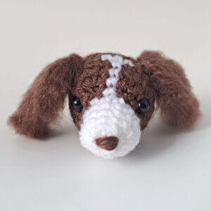 An adorable little spaniel brooch in brown and white with fluffy ears and a lovely expression