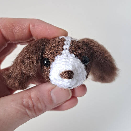 A spaniel animal head crochet brooch in a hand