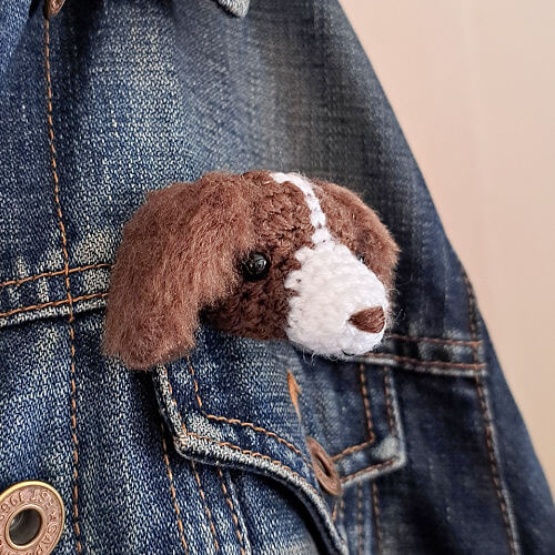 A spaniel animal head crochet brooch on a denim jacket from the side