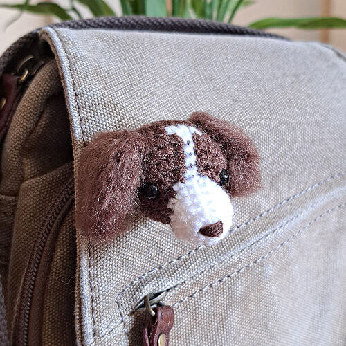 A spaniel animal head crochet brooch shown on a canvas handbag