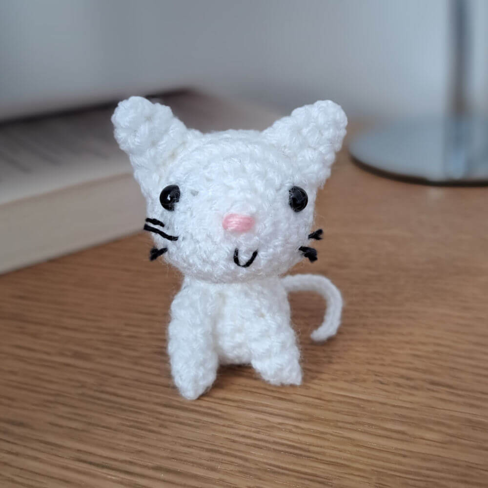 white cat ornament, small crochet cat sitting on a bedside table